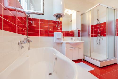 a bathroom with a white tub and red tiles at VILLA ALEXANDRA in Kumbor