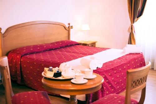 a bedroom with a bed and a table with cups and saucers at HG Abetone e Piramidi Resort in Abetone