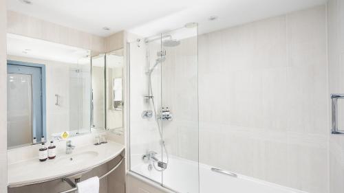 a white bathroom with a shower and a sink at voco St. David's Cardiff by IHG in Cardiff