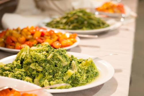 a table topped with plates of broccoli and vegetables at HG Abetone e Piramidi Resort in Abetone
