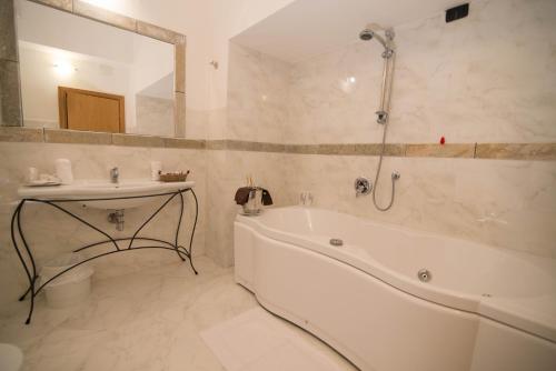 a white bathroom with a tub and a sink at HG Abetone e Piramidi Resort in Abetone