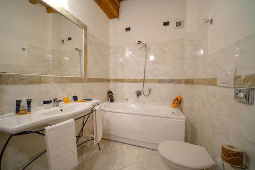 a bathroom with a tub and a sink and a toilet at HG Abetone e Piramidi Resort in Abetone