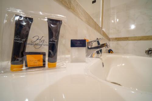 a bathroom sink with toothbrushes andodorizers on it at HG Abetone e Piramidi Resort in Abetone