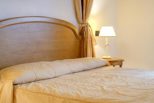 a bed in a bedroom with a lamp on a table at HG Abetone e Piramidi Resort in Abetone