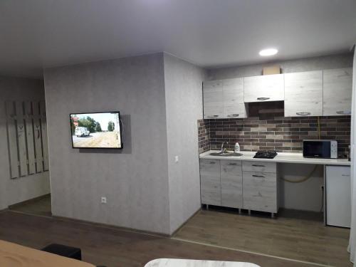 a kitchen with white cabinets and a tv on the wall at Stefan 16-50 in Bălţi