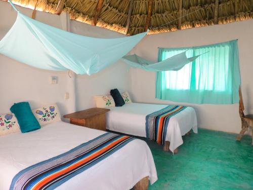 a bedroom with two beds and a window at Cabañas Calakmul in Conhuas