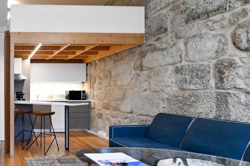 a living room with a blue couch and a stone wall at Oporto Chic&Cozy - Ribeira in Porto