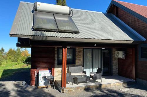 a house with a deck with chairs and a heater at Agréable chalet Au milieu des sapins in La Plaine des Cafres