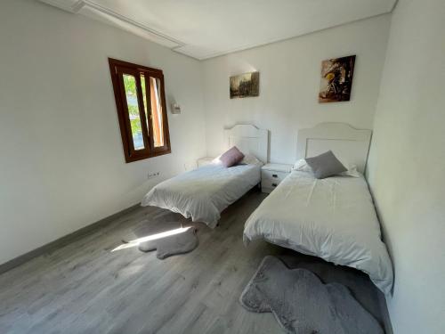 two beds in a room with white walls and wooden floors at Villa nueva 1910 in Getxo