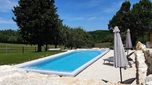 - une piscine avec un parasol et une chaise dans l'établissement Ferme Brasseyrou - B&B classique, à Dévillac