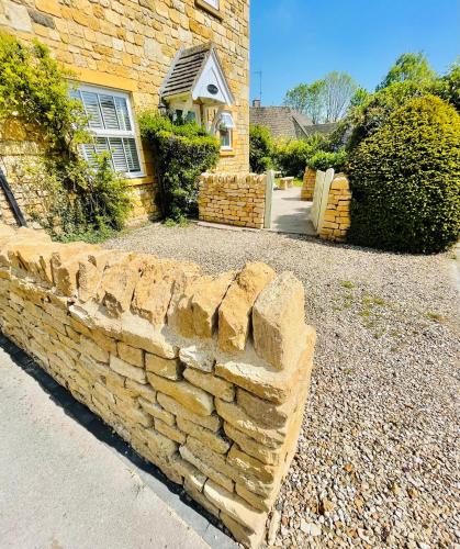 a brick retaining wall in front of a house at Cotswold Chic Retreats "Jacinabox" Central Chipping Campden-Parking-Garden in Chipping Campden