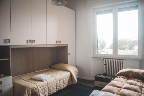 1 dormitorio con 2 camas, armarios blancos y ventana en NOVA DOMUS FLAT Free Private Parking, en Siena