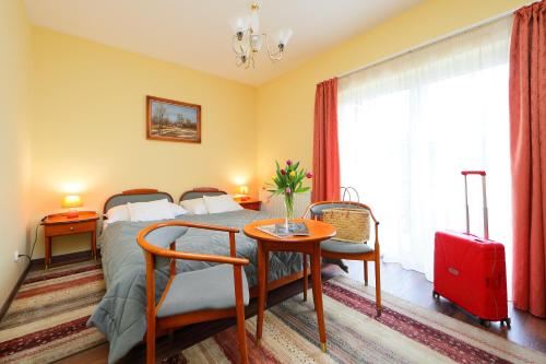 a bedroom with a bed and a table with a red suitcase at Balazs Villa in Balatonfüred
