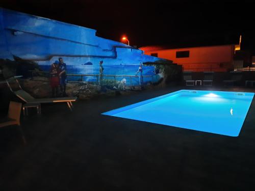 uma piscina iluminada à noite em Hotel I Colori em SantʼAntìoco