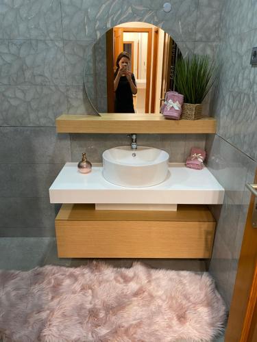 una mujer tomando una foto de un lavabo en un baño en Vagueira casa férias en Aveiro