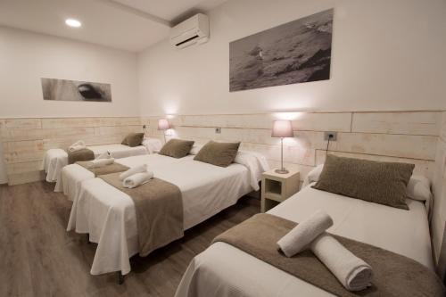 4 camas en una habitación con paredes blancas en Pensión San Martin, en San Sebastián