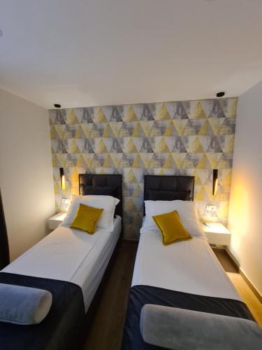 two beds in a hotel room with yellow pillows at Apartman Kamena 67 A in Tučepi
