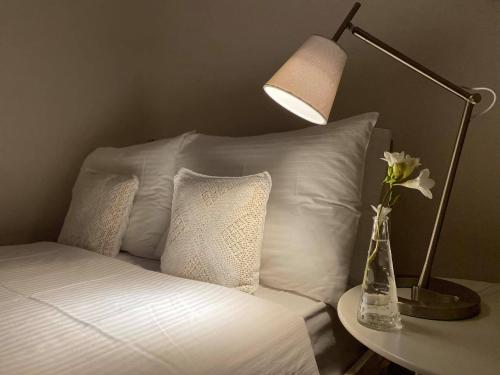 a bed with a lamp and a vase with flowers on a table at Rebekka's HOUSE in Zákros