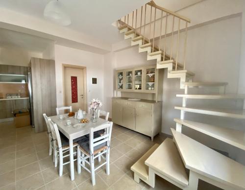a dining room with a white table and a staircase at Rebekka's HOUSE in Zákros