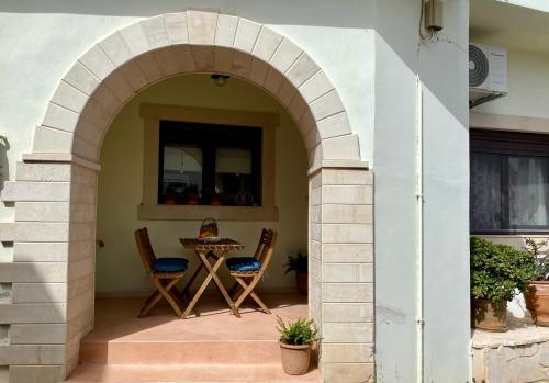 an archway in a patio with a table and chairs at Rebekka's HOUSE in Zákros