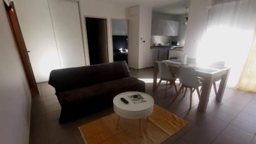 a living room with a couch and a table at Appartement T2 accessible PMR avec terrasse et garage in Onet le Château