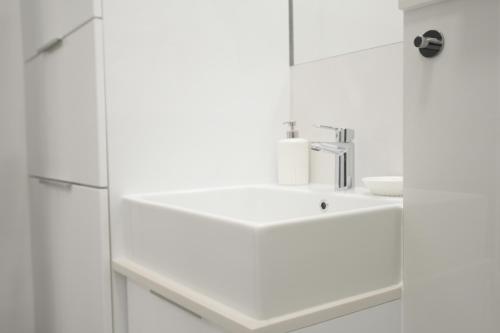a white bathroom with a sink and a mirror at Blue Sky Apartments Rezydencja Niechorze - 302 in Niechorze