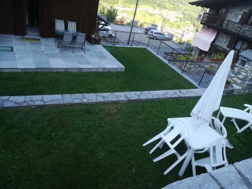 a white umbrella and a chair on the grass at Appartamento con vista chez Mary in Roisan