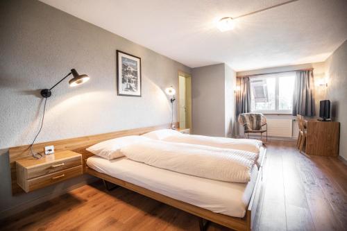 a bedroom with a bed and a desk and a window at Berggasthaus Crest'ota in Lenzerheide