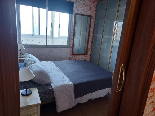 una camera con letto, specchio e finestra di Apartment on the beach and ocean sounds a Fasnia