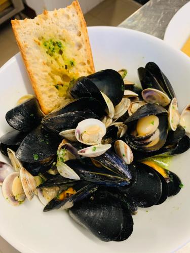 a plate of mussels with a slice of bread and a sandwich at Relais Real Collegio in Noli