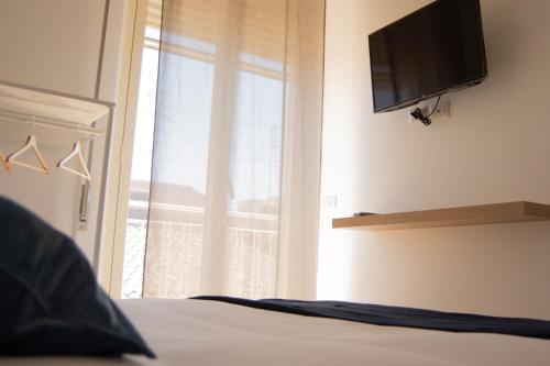 a bedroom with a bed with a television and a window at Casa Vacanze Caramagna in Aci Castello