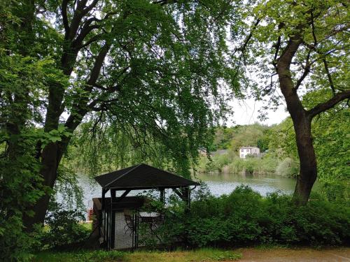 a gazebo in front of a river with trees at 4 Sterne-Haus am See in Waren