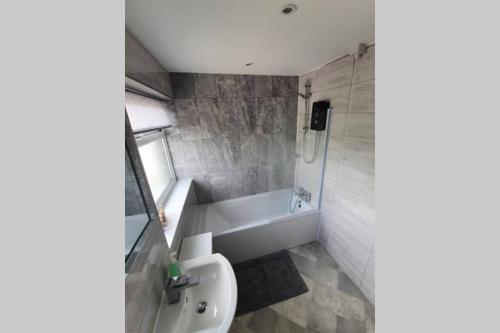 a bathroom with a sink and a toilet and a tub at Entire House - Cheshire Oaks/Ellesmere Port in Ellesmere Port