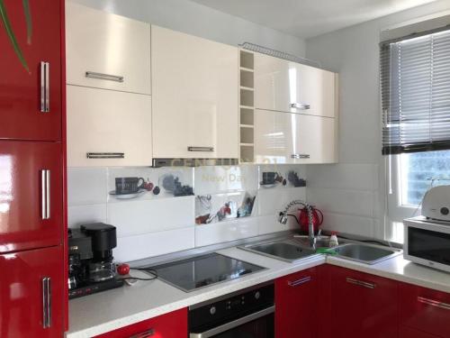 a kitchen with white appliances and red cabinets at Sea View Apartment in Durrës