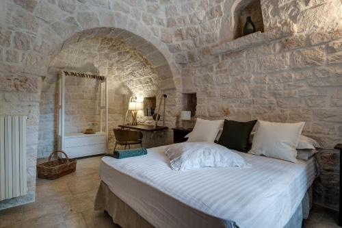 a bedroom with a large bed in a stone wall at Il Sassofono in Cisternino