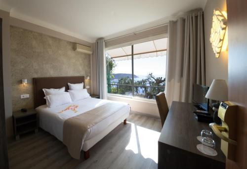 ロクブリュヌ・カップ・マルタンにあるオテル ドゥ シャルム リージェンシーのベッドと大きな窓が備わるホテルルームです。