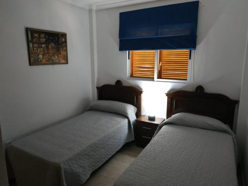 dwa łóżka w małym pokoju z oknem w obiekcie casa vacacional Veramar 2 Vera Playa w mieście Playas de Vera