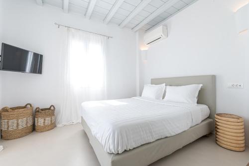 a white bedroom with a bed and a tv at Carpe Diem Villas Mykonos ,Heated Pool! in Ornos