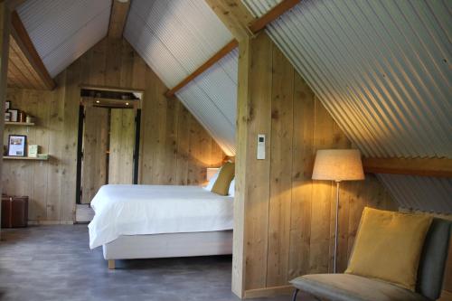 - une chambre mansardée avec un lit et une chaise dans l'établissement Inn The Woods - Private Stay, à Overberg