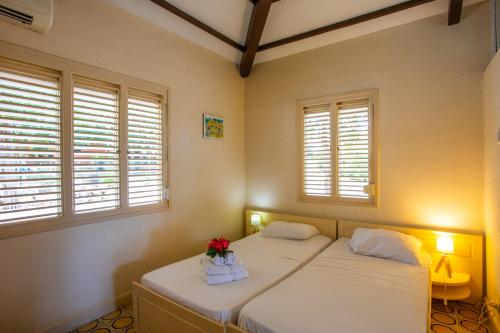 a bedroom with two beds with flowers and windows at Bungalow Hopi Bon in Willemstad