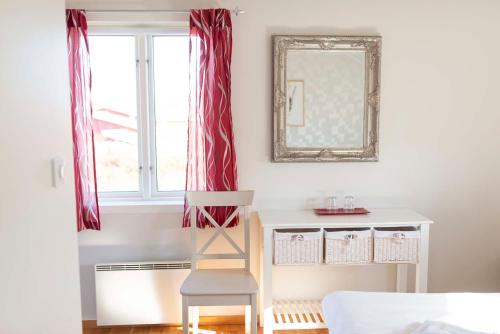 a chair in front of a window with a mirror at Prästgårdens Pensionat in Mollösund