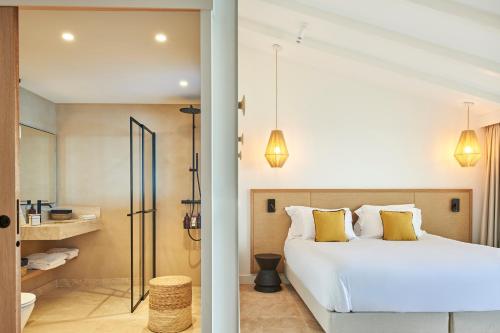 a bedroom with a white bed and a bathroom at Les Roches Brunes in Collioure