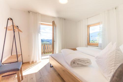a bedroom with a bed and a chair and a window at Apartment La Brunella in Laion