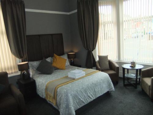 a bedroom with a bed and a chair and windows at Dewsbury House in Blackpool