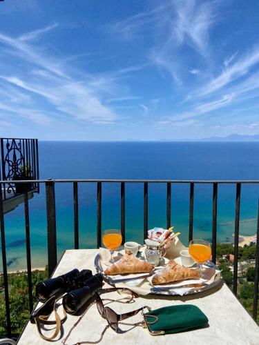 a table with food and drinks on a balcony with the ocean at Residenza Porta di Mare in Castellabate