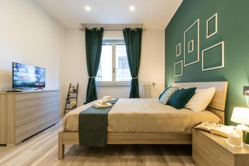 um quarto com uma cama com paredes verdes e uma televisão em Green Pearl ✰✰✰✰✰ Appartamento a 100 metri dal lago em Arona