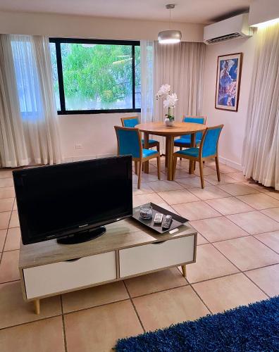 a living room with a tv and a table with chairs at Hermosa suite de playa, con vista al golf en Coronado in Playa Coronado