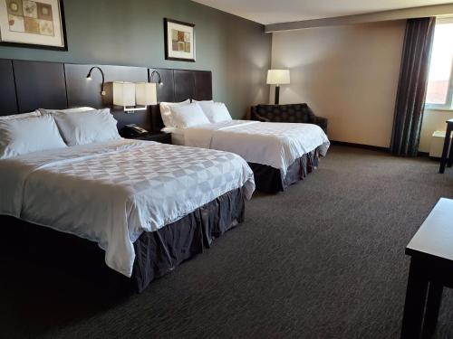 a hotel room with two beds and a chair at Holiday Inn Saskatoon Downtown by IHG in Saskatoon