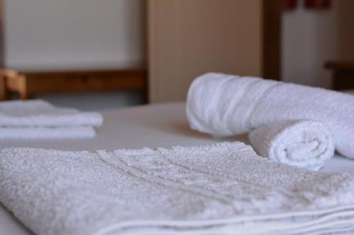 a pile of white towels sitting on top of a bed at Avra Studios in Elafonisos