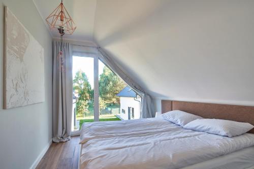 a bedroom with a bed and a large window at SosnowoMi - Całoroczne domy na wynajem in Lubiatowo